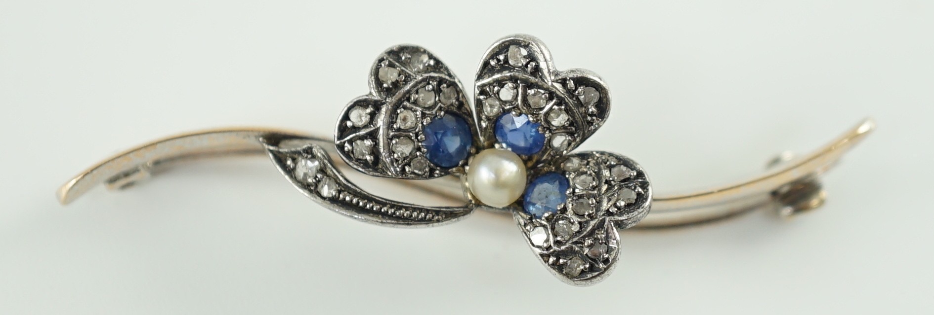 A 1920’s white gold, sapphire, cultured pearl and rose cut diamond set shamrock bar brooch